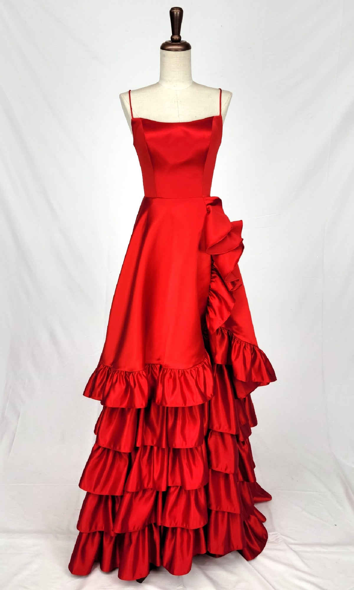 The Lace-Up Ruffled Long Prom Dress: Chicas C826 is a red sleeveless flamenco-style gown with a square neckline, layered A-line skirt, large side ruffle, and an elegant lace-up back, displayed on a mannequin.