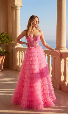 A woman stands on a balcony in the Chicas C833 Long Prom Dress in pink, featuring tiered ruffles, a lace embroidered bodice, and a sweetheart neckline, smiling as she gazes into the distance.