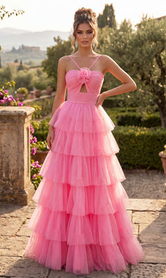 A woman stands outdoors amid lush greenery and distant buildings, wearing the Chicas C837 Long Prom Dress in pink—a floor-length, sleeveless ball gown crafted from layered tulle with a floral detail on the bodice and a dramatic, tiered full skirt.