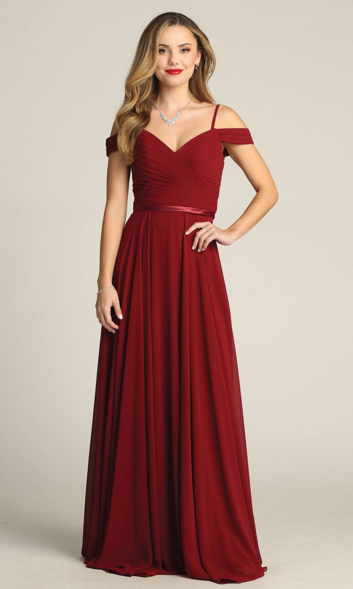 A woman wears the Chicas C8997, a long A-line off-shoulder prom dress in burgundy with a sweetheart neckline and fitted bodice, creating an elegant formal evening look.