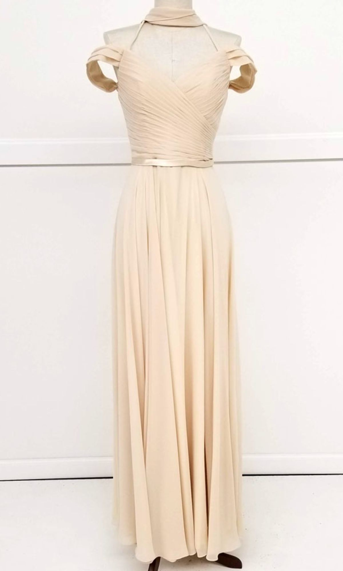 The Chicas C8997 is a long A-line off-shoulder prom dress in cream, featuring a pleated bodice and flowing skirt, displayed on a dress form against a plain white background.