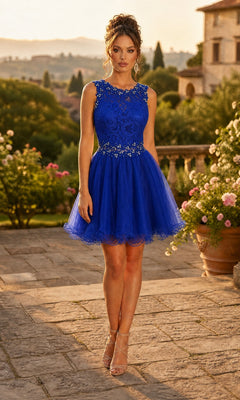 A woman stands outdoors surrounded by greenery and stone buildings, wearing the Chicas C9350 short homecoming dress in royal, which features a sleeveless knee-length design with an illusion lace bodice adorned with bead detailing.
