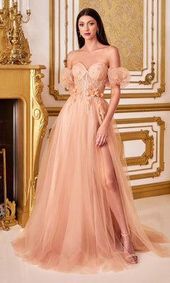 A woman stands by a gold fireplace in an ornate room, wearing the Ladivine CB080 Glitter Tulle Ball Gown Prom Dress—peach-colored, off-the-shoulder, with floral details, a corset bodice, and a thigh-high slit.