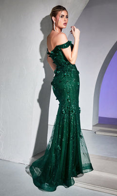 A woman stands indoors, looking over her shoulder in the elegant Emerald Green Off-Shoulder Long Prom Dress CB096, featuring floral embellishments that highlight its sophisticated style.