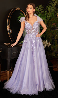 A woman wearing the Ladivine Long Formal Dress CB097 in lavender with floral appliqué and sheer cap sleeves stands in a room with plants, a black vanity, and a round mirror.