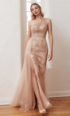 A woman in the One-Shoulder Rose Gold Long Formal Gown CB098 with sequin embellishments and a high slit stands on a wooden floor by a window.