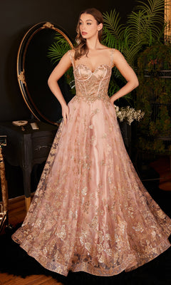 A woman stands indoors wearing the Butterfly-Print Long Corset Prom Ball Gown CB102, a floor-length dress featuring a blush pink hue, gold floral embroidery, sheer straps, and an elegant A-line silhouette. She poses with her hands on her waist.