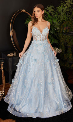 A woman wears the Ladivine Long Formal Dress CB105, featuring a blue ball gown design with 3D floral details and a sheer corset bodice, standing indoors beside a mirror and lush green plants.
