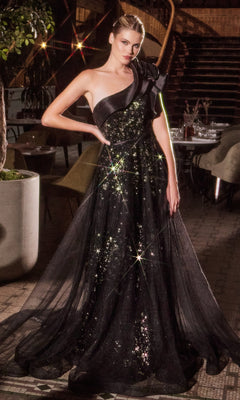 A woman stands indoors by chairs, plants, and a staircase, wearing the elegant Ladivine CB157 One-Shoulder Long Black Prom Dress with sparkling details.