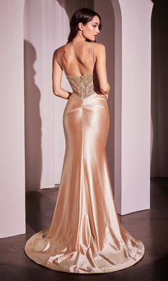 A woman stands in an arched doorway wearing the Beaded-Bodice Long Prom Dress (Ladivine CC0238), a gold, floor-length satin gown with a backless design, v-neck, thin straps, pearlized beading, and a small train.