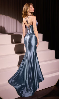 A woman wearing the Long Corset Glitter Prom Dress: Ladivine CC2397, a shiny fitted blue gown with a lace-up back, stands on light-colored steps facing away from the camera.