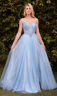 A woman stands outdoors in the Ladivine CC415 Beaded-Bodice Long Prom Dress, featuring a light blue bodice and tulle skirt, surrounded by green leafy bushes.