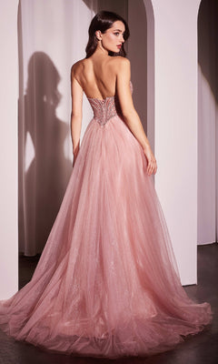 A woman in the Beaded-Bodice Long Prom Dress: Ladivine CC415, featuring a strapless fitted bodice and flowing tulle skirt, stands with her back to the camera in a softly lit room.