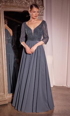 A woman in the Modest Long A-Line Formal Dress: Ladivine CC446, featuring a floor-length slate blue design with sheer three-quarter sleeves and a deep V-neckline, stands before a large ornate mirror.