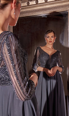 A woman in the Ladivine CC446 Modest Long A-Line Formal Dress with sheer beaded sleeves stands before a large mirror, gracefully admiring her reflection.