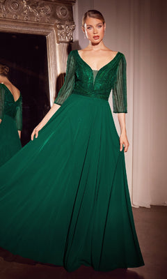 A woman stands indoors before a large ornate mirror, wearing the Ladivine CC446 Modest Long A-Line Formal Dress in emerald green with sheer three-quarter sleeves—a stunning choice for a mother of the bride gown.