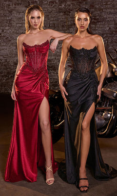 Two women in evening gowns standing in front of a car with a brick wall background.