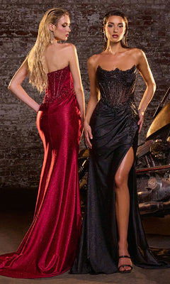 Two women in elegant evening gowns standing against a rustic brick wall.