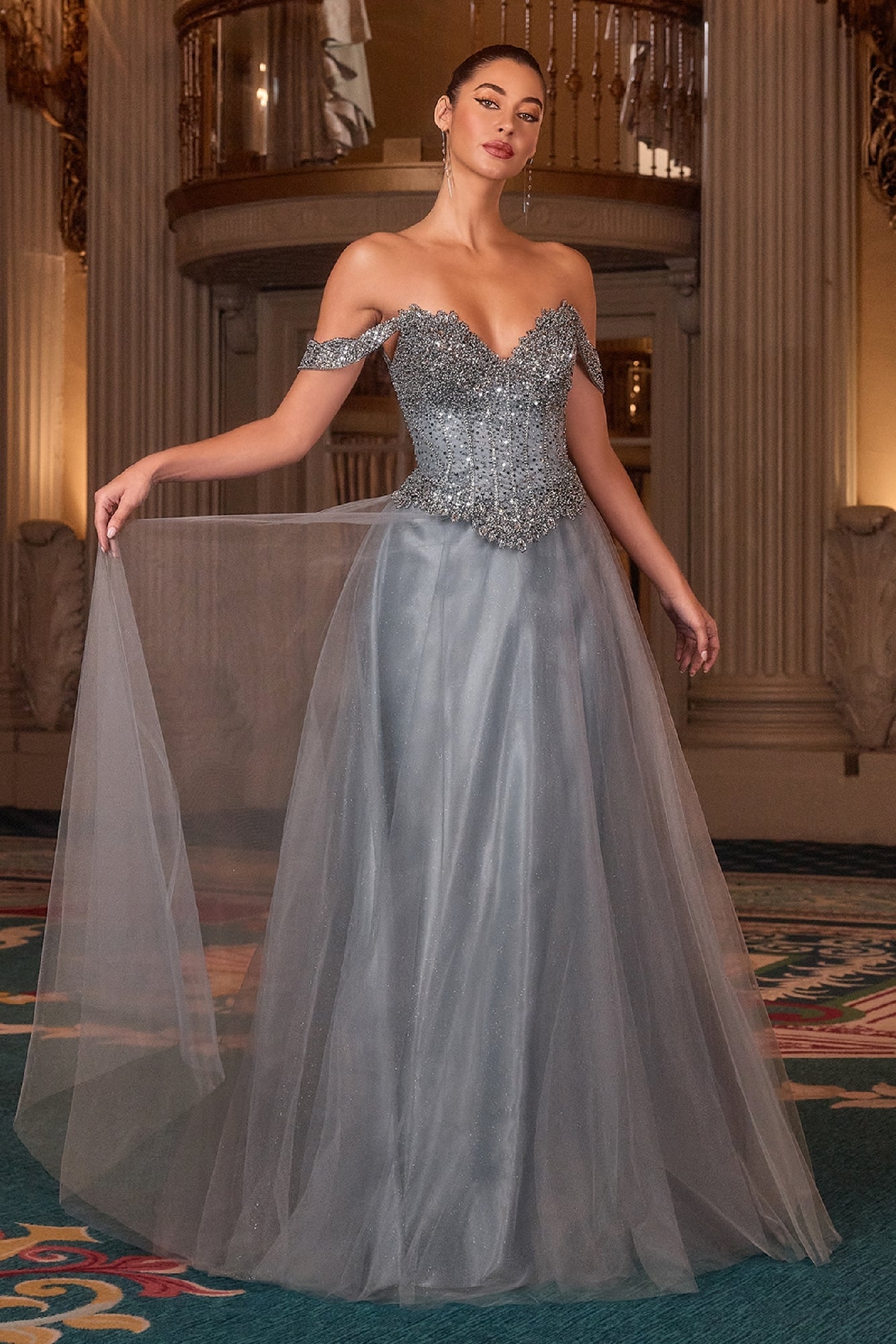 Woman in a smoky blue evening gown with a chandelier in the background