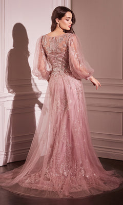 A woman stands indoors wearing the Ladivine CD0102 Sheer-Sleeve Long Prom Dress—a pink glittery evening gown with voluminous sleeves and a flowing train—turned slightly to the side.