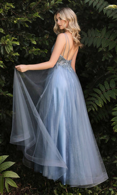 A woman in the Sheer-Corset Long Prom Ball Gown CD0154, a light blue, floor-length dress with a sheer overlay and beaded embellishments, stands outdoors near green foliage, looking over her shoulder.