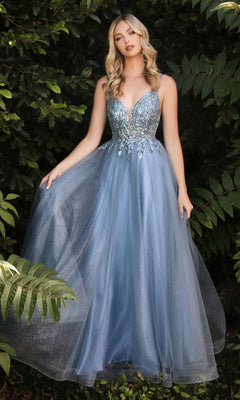 A woman stands outdoors among green plants wearing the Sheer-Corset Long Prom Ball Gown CD0154, a sparkly light blue sleeveless dress with a deep V neckline and beaded embellishments.