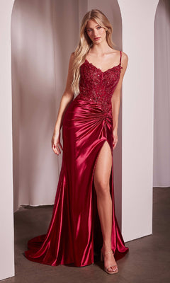 A woman in the Twist-Front Sheer-Waist Long Prom Dress CLCD0176—a sleeveless, floor-length red gown with lace bodice, twist-front detail, and thigh-high slit—stands before white archways.