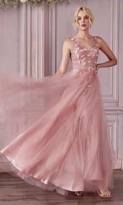 A woman stands before light-paneled walls wearing the Glitter Tulle Illusion Prom Dress (Ladivine CD0181), a sleeveless blush pink gown with a floral appliqué bodice and flowing tulle skirt.