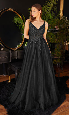 A woman stands indoors wearing the Glitter Tulle Illusion Prom Dress: Ladivine CD0181, a long black gown with floral embroidery. She gazes to the side, with plants and décor visible in the background.