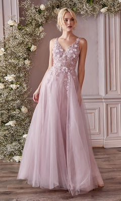 A woman wearing the Glitter Tulle Illusion Prom Dress: Ladivine CD0181, a light pink, floor-length gown with floral appliqué, stands before an arch adorned with white flowers and greenery.