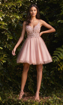A woman stands outdoors before green foliage, wearing the Lace-Bodice Short A-Line Homecoming Dress CD0190—featuring a sheer lace bodice and tulle skirt—paired with nude heels.