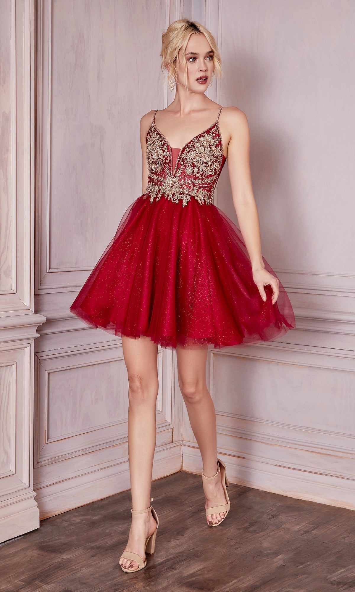 A woman poses in nude heels against a decorative wall, wearing the Lace-Bodice Short A-Line Homecoming Dress CD0190—featuring red tulle, gold embroidery, and a sheer lace bodice.