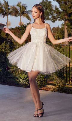 A woman stands outdoors in the Embellished Short A-Line Homecoming Dress CD0212—sleeveless, white, knee-length with a tulle skirt—wearing black heels and surrounded by greenery.