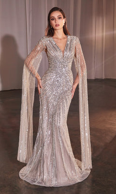 A woman models the Ladivine CD0239 Cape-Sleeve Beaded Formal Dress—a floor-length silver sequin gown with a fitted bodice, deep V-neckline, and sheer cape sleeves—against a simple indoor backdrop.