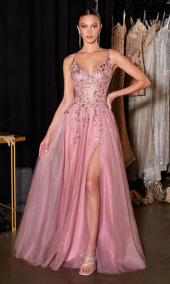 A woman wears the mauve Ladivine CD2412 long prom dress, featuring a sleeveless design, beaded embellishments, and a high slit, standing in a dressing room with dresses hanging in the background.