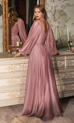 A woman wearing the Ladivine Plus-Size Off-Shoulder Prom Dress CD243C stands by a vintage dresser, her back partly turned to a mirror in a softly decorated room with floral wallpaper.
