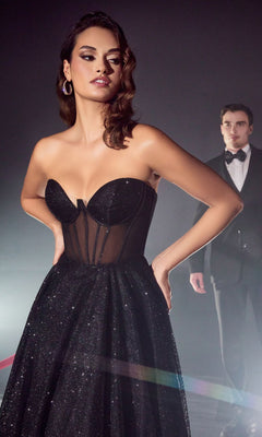 A woman in a Strapless Sheer-Corset Glitter Prom Ball Gown CD275 stands in the foreground, while a man in a tuxedo stands in the background.