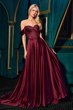 A woman in a Ladivine CD297 Strapless Long A-Line Prom Dress stands in an elegant room with green velvet curtains and gold accents, wearing a burgundy satin off-the-shoulder gown.