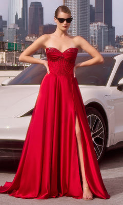 A woman wearing the Ladivine CD297 Strapless Long A-Line Prom Dress, featuring a beaded corset and high slit, poses in front of a white car with sunglasses against a city skyline backdrop.