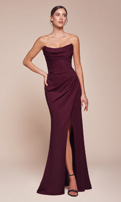 A woman in the Lace-Up Strapless Long Prom Gown: Ladivine CD355, a burgundy dress with a draped bodice and thigh-high slit, stands against a plain beige background.