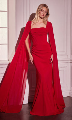 A woman stands indoors wearing the Formal Dress with Cape Sleeves: Ladivine CD356, a fitted, floor-length red gown featuring a square neckline and dramatic cape sleeves—ideal for making an entrance at any prom or formal event.