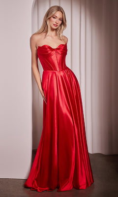 Woman modeling the Ladivine CD378 Strapless Long A-Line Prom Dress with a corset-style bodice and flowing red satin skirt, standing indoors against a white curtain backdrop.