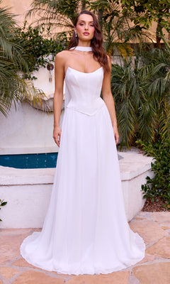 Woman in a white strapless gown standing outdoors with greenery and a fountain in the background