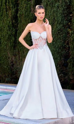 A woman poses outdoors near lush greenery and a sparkling pool, wearing the Ladivine CD389W Long White Prom Dress in off white, featuring a strapless sheer corset bodice and a full Mikado skirt.