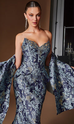 A woman poses against a neutral background wearing the Ladivine CD655 long formal dress, an ornate strapless blue and silver floral jacquard evening gown featuring a corset bodice and dramatic sleeves.