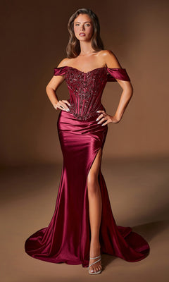 A woman poses in the Ladivine CD656, a fitted burgundy satin prom dress with an off-the-shoulder embellished corset bodice and high leg slit, paired with strappy heels against a plain brown background.