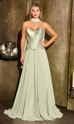 A woman wearing the Ladivine CD668 long prom dress in sage, featuring a strapless satin corset bodice and a flowing chiffon A-line skirt, stands indoors against a textured wall.