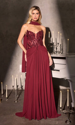 A woman in the Ladivine CD673 long burgundy prom dress with a beaded corset bodice and lace detailing stands beside a white piano and lit candles.