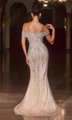 A woman stands on a shiny floor in the Ladivine CD674 long prom dress, an off-the-shoulder, fitted nude sequin gown with silver accents and a subtle mermaid hem, facing away in an elegant, dimly lit interior.