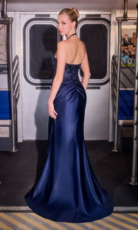 A woman in a deep blue Sheer-Corset Long Halter Prom Gown (Ladivine CD690) stands inside a subway car, facing away from the camera in the open-back, fitted bodice dress.
